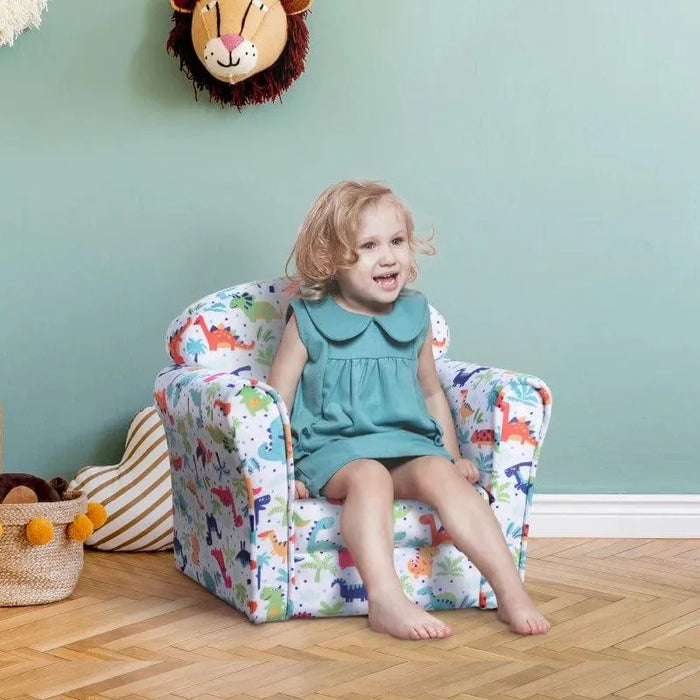 Smiling toddler sitting on multicolour dinosaur kids armchair in playful room