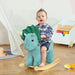 Toddler riding dark green triceratops dinosaur rocking horse toy in playroom