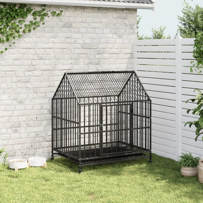 Heavy duty galvanized steel dog cage with wheels in garden, beside white fence and wall