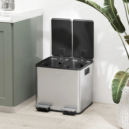 Modern double kitchen pedal bin with soft-close lids in stainless steel beside green cabinet and plant