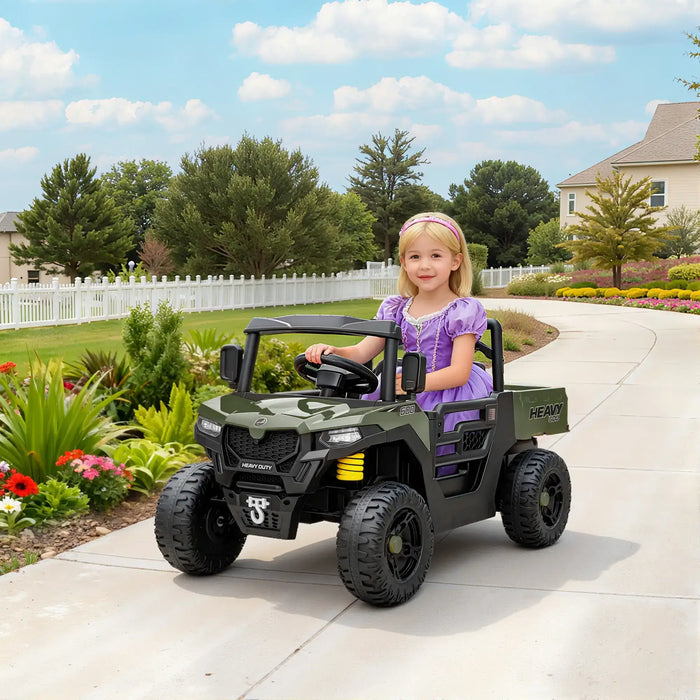 Child in a purple dress sitting in a green toy truck on a driveway with a garden and house in the background.