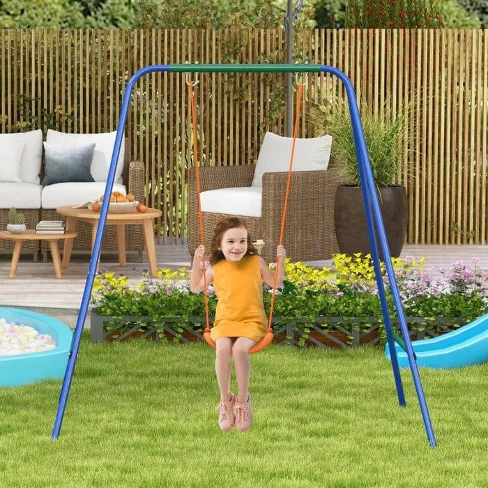 Child on a dual seat kids swing set with A-frame in a backyard garden with patio furniture