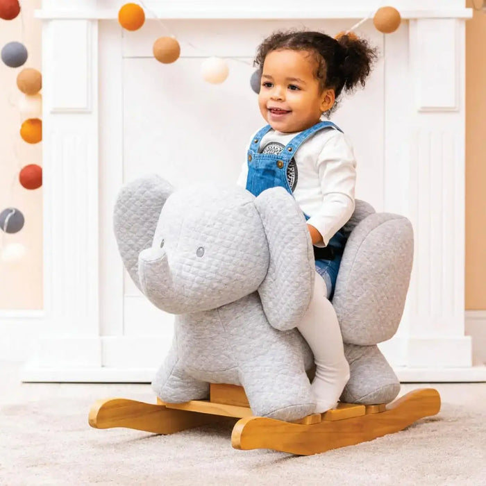 Child riding a gray elephant-shaped rocking toy indoors.
