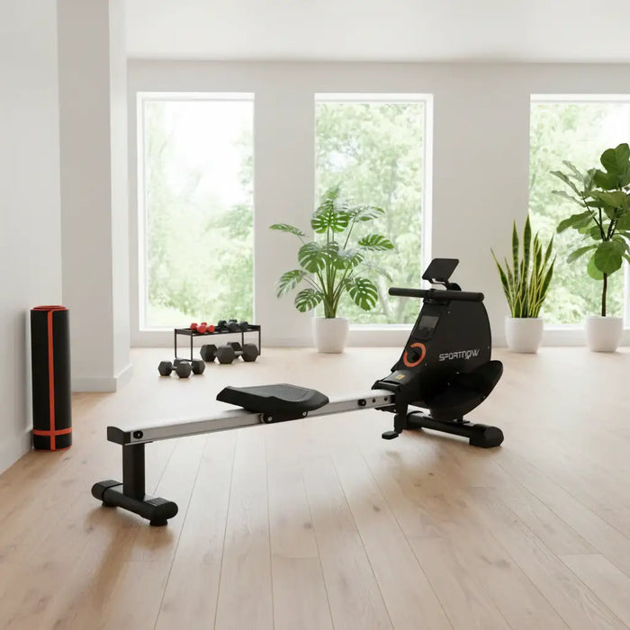 Rowing machine with digital display in a plush lounge with a plant and weights in the background