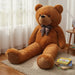Large brown teddy bear with a bow tie sitting on a carpeted floor.