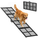 Dog using a black mesh pet ramp on a white background