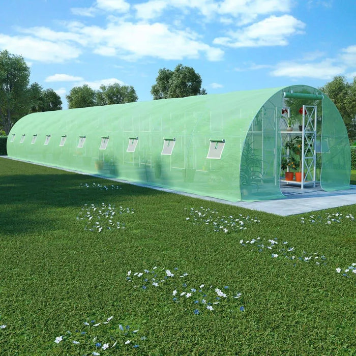 Extra long green polytunnel greenhouse with mesh cover on grassy lawn under blue sky