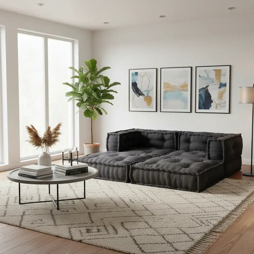 Modern living room with a dark gray sectional sofa, round coffee table, and abstract art on the wall.