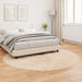 Neatly made bed in a bedroom with light wood flooring and white walls.