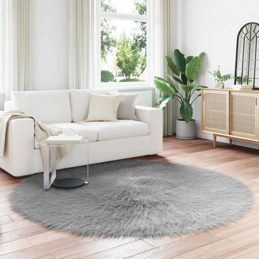 Round gray rug on a wooden floor in a living room with a white sofa and decorative items.