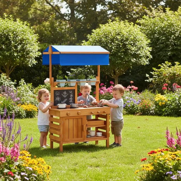 Three children playing with a wooden outdoor play kitchen with blue canopy in a colorful garden
