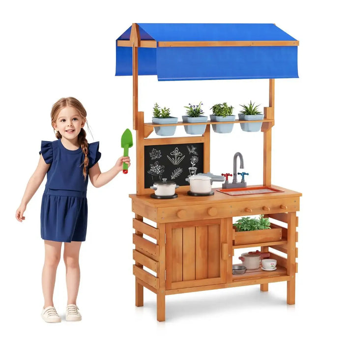 Young girl playing with natural wood play kitchen featuring blue adjustable canopy and potted plants