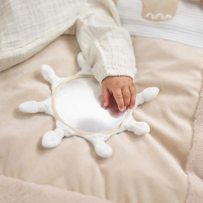 Baby hand holding a white star-shaped toy on a soft beige surface