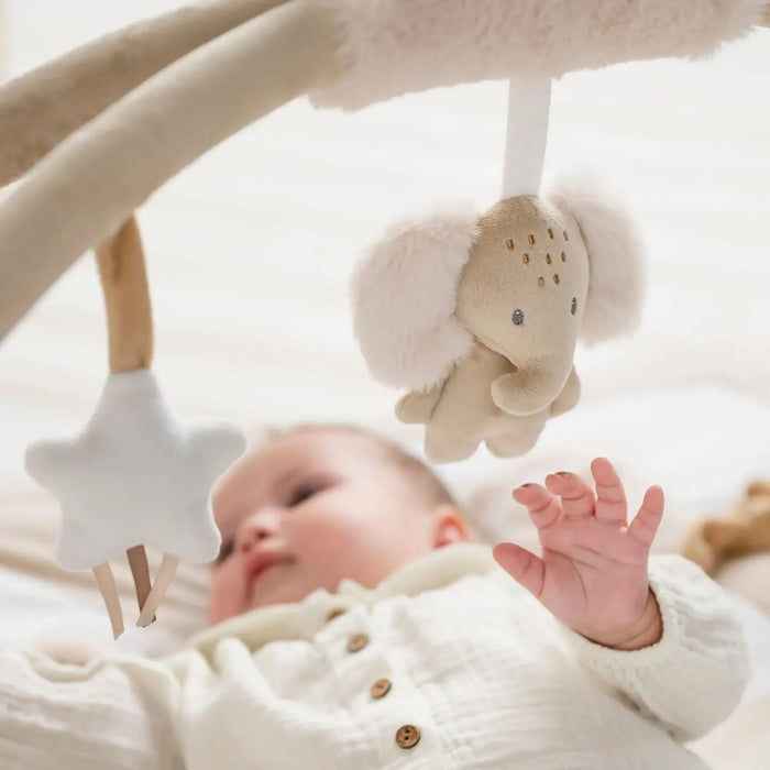 Baby playing with a hanging toy in a crib