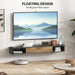 Floating black and wood TV cabinet mounted on wall with decor and cable management in modern living room