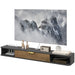 Floating TV cabinet in black and wood finish with cable management, decorated with cat figurines, clock, radio, and books