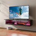 Floating black TV stand with LED lights holding decorative items, mounted on beige wall with a large flat-screen TV playing snowboarding