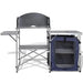 Foldable camping kitchen unit with metal tabletop, side shelves, and blue storage compartment.