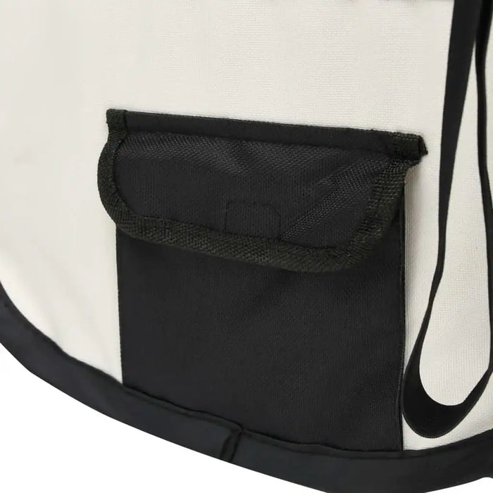 Close-up of black pocket on foldable dog playpen in cream and black fabric