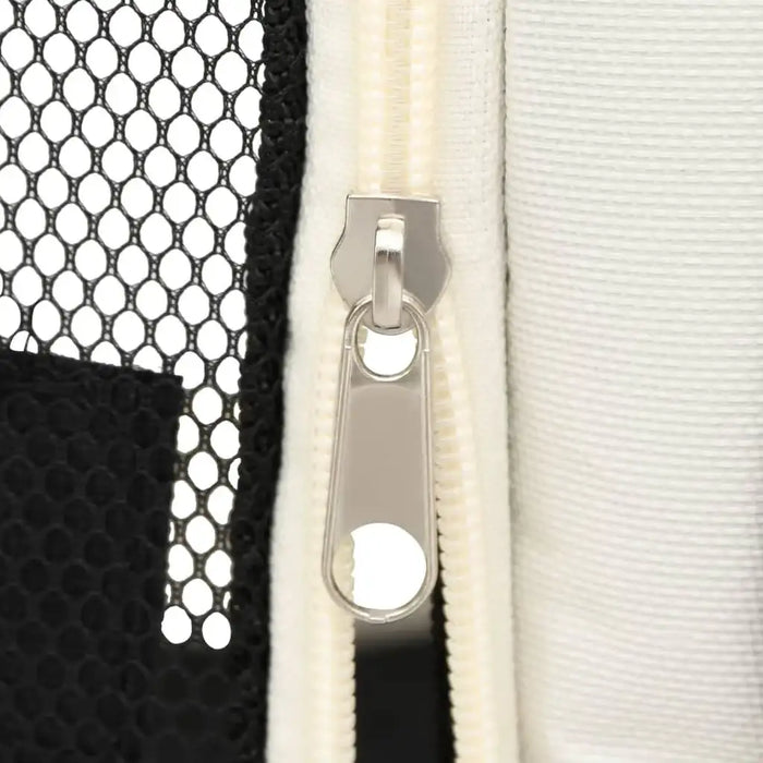 Close-up of a silver zipper on a black mesh and cream fabric foldable dog playpen