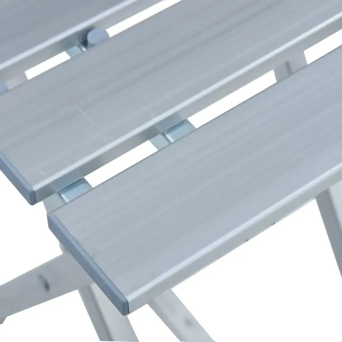 Close-up of silver folding aluminum camp stool with slatted seat, lightweight design