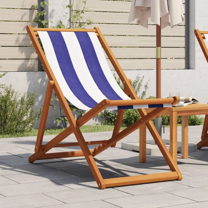 Blue and white striped folding beach chair with solid wood eucalyptus frame on patio