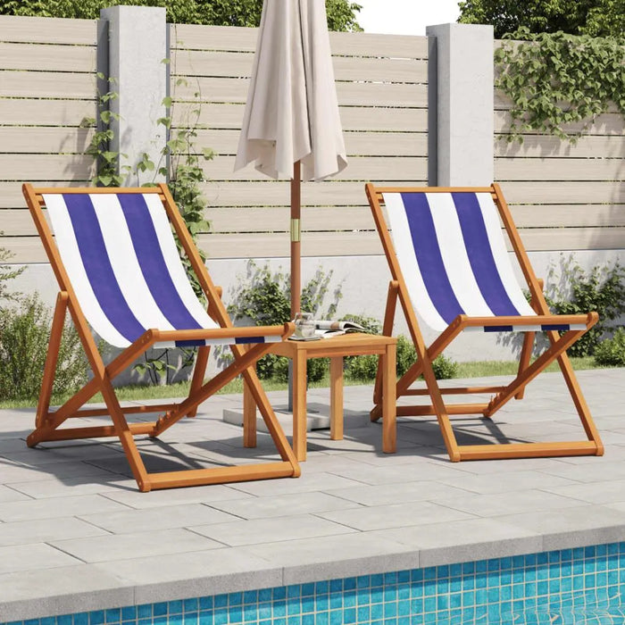 Blue and white striped folding beach chairs with wood frames by a poolside