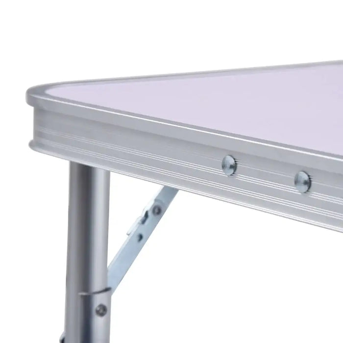 Close-up of lightweight aluminum folding camping table with white tabletop and metal frame
