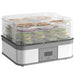 Food dehydrator with transparent trays holding various food items on a white background