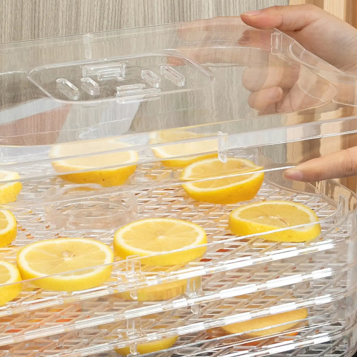 Clear food dehydrator tray with lemon slices being held by a person.