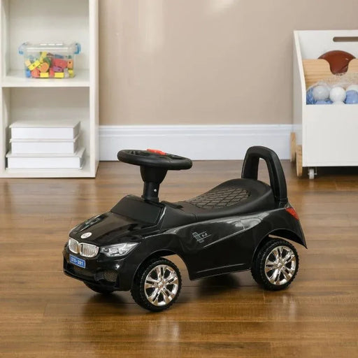 Black foot-to-floor ride-on car for toddlers with steering wheel on wooden floor