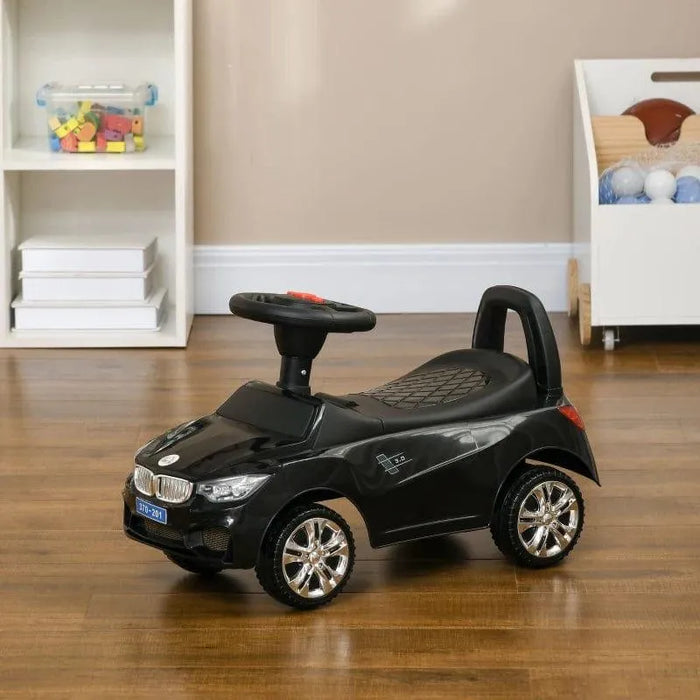 Black foot-to-floor ride-on car for toddlers with steering wheel on wooden floor