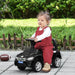 Toddler riding black foot-to-floor ride-on car with chrome wheels outdoors
