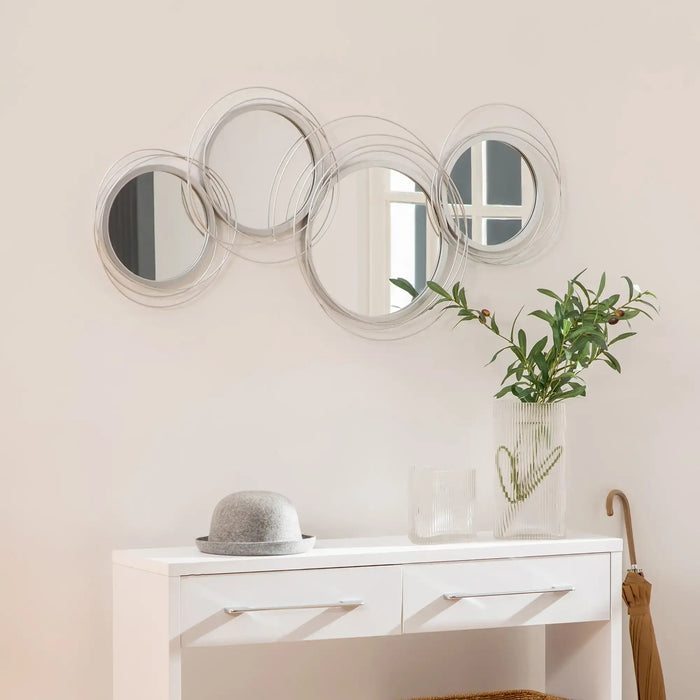 Decorative wall mirror with circular design above a white console table.