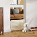 White dog sitting on a wooden floor in a living room with a radiator and furniture.