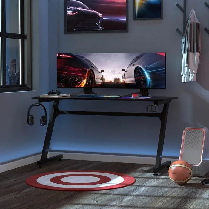 Black gaming desk with Z shape frame, cable management, headphone hook, and ultra-wide monitor
