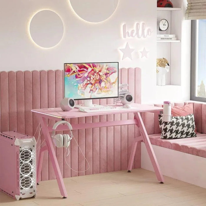 Pink gaming desk with RGB LED lights, monitor, speakers, pink PC case, and stylish decor