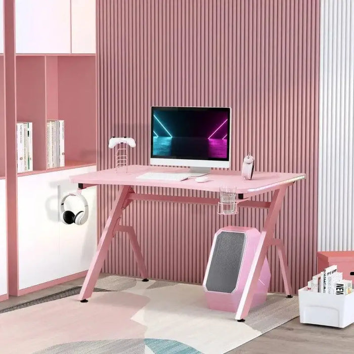 Pink carbon fibre style gaming desk with computer monitor, headset, and gaming accessories