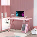 Pink carbon fibre style gaming desk with computer monitor, headset, and gaming accessories