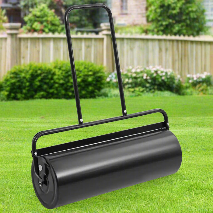 Black heavy duty iron lawn roller with handle on green grass in a garden setting