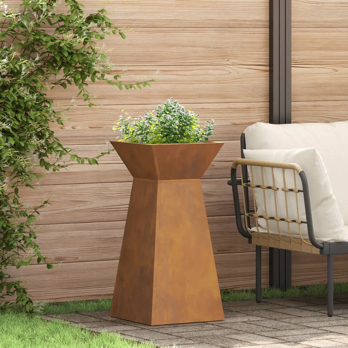 Modern weathering steel garden pillar planter with green plants, next to outdoor chair on patio