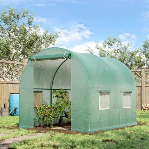 Green polytunnel greenhouse with roll-up door and side windows in a sunny backyard