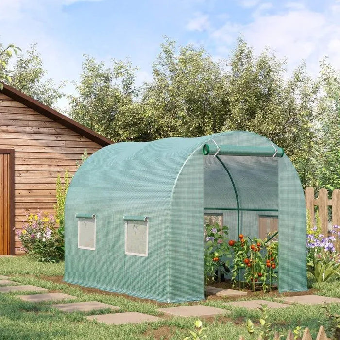 Green walk-in polytunnel greenhouse with roll-up door and side windows in garden
