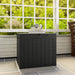 Black waterproof garden storage box with handles on tiled patio under white window, books and headphones on top