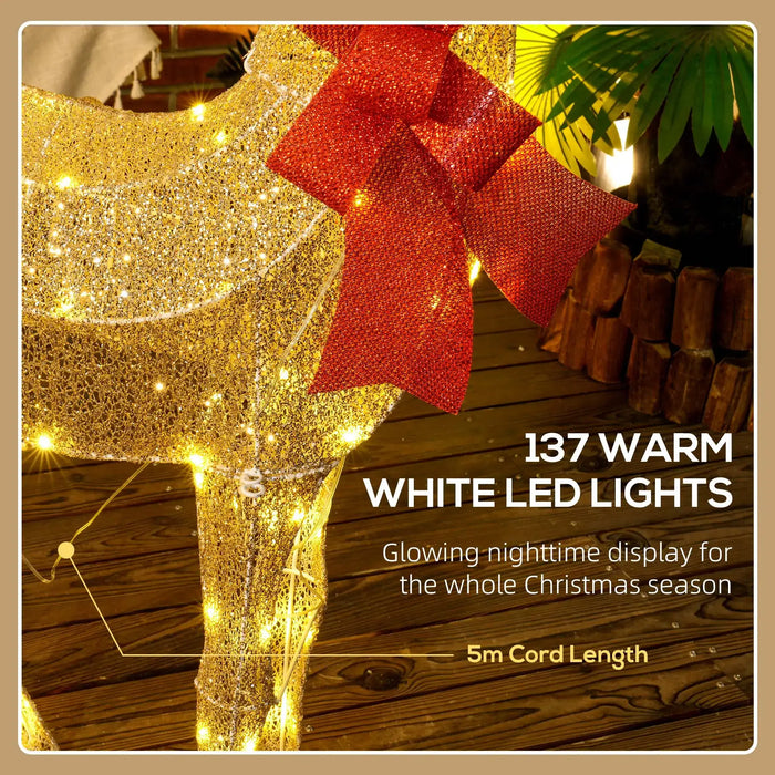 Golden glittering reindeer decoration with 137 warm white LED lights and red mesh bow on wooden floor
