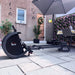 Rowing machine on a patio with a house and garden in the background