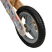 Close-up of grey balance bike wheel with black tire and playful plywood frame design