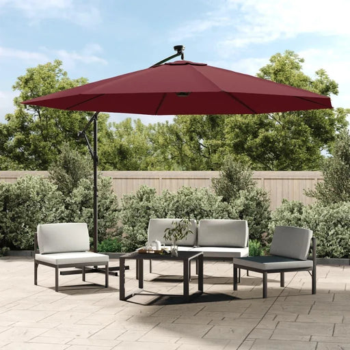 Bordeaux red hanging parasol with LED lights over modern outdoor patio furniture