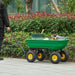 Heavy duty green garden dump cart with yellow wheels, loaded with tools, on outdoor path