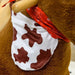 Brown plush rocking horse with white and brown cow-print bandana and red scarf detail